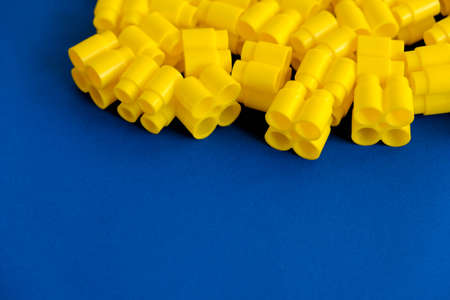 Yellow plastic building blocks on yellow background. Background of plastic details building blocks. Parts of bright small spare parts for toys. Top view. Copy, empty space for text.の写真素材