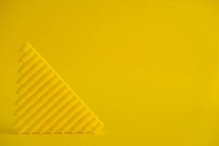 Yellow plastic building blocks in the shape of a pyramid on yellow background. Background of plastic...