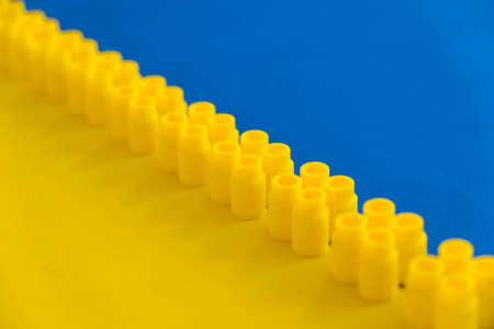 Yellow plastic building blocks in the shape of a tower on yellow background. Background of plastic details building blocks. Parts of bright small spare parts for toys. Copy, empty space for text.の写真素材