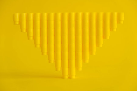 Yellow plastic building blocks in the shape of a tower on yellow background. Background of plastic...