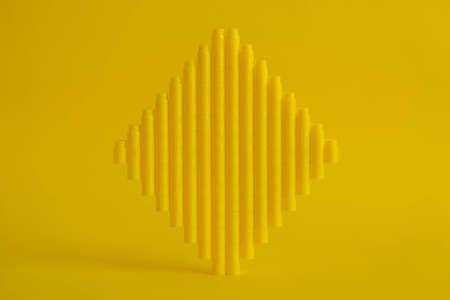 Yellow plastic building blocks in the shape of a tower on yellow background. Background of plastic details building blocks. Parts of bright small spare parts for toys. Copy, empty space for text.の写真素材