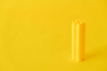 Yellow plastic building blocks in the shape of a tower on yellow background. Background of plastic details building blocks. Parts of bright small spare parts for toys. Copy, empty space for text.の写真素材