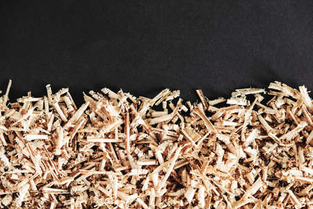 Wood shavings on black background. Background of fresh wood shavings. Copy, empty space for text.の写真素材