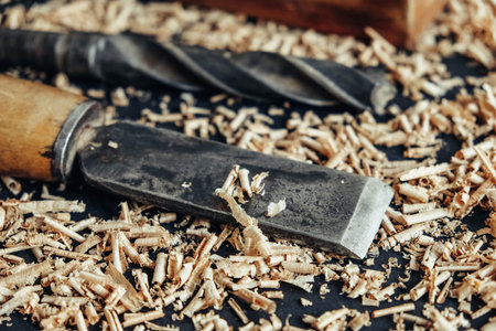 Wood drill bit with wooden shavings on black background. Copy, empty space for text.