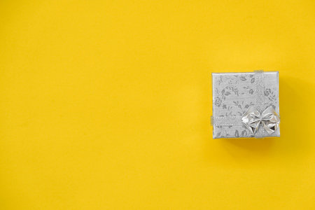 Silver gift box on yellow background. Top view. Copy, empty space for text.