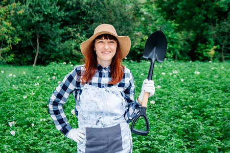 Beautiful woman farmer sitting on a blanket near fresh organic vegetables in a wooden box against the background of a vegetable garden. Copy, empty space for text.の写真素材