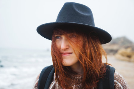 Portrait of a beautiful red-haired woman in a hat. Place for text or advertising.