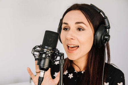 Portrait of beautiful woman in headphones sings a song near a microphone in a recording studio .. Place for text or advertising.の写真素材