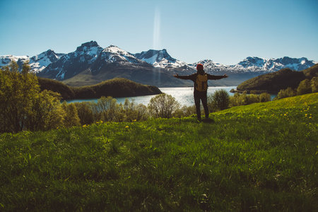 Traveler man is standing in the middle of a forest with a guitar on background of mountains and...