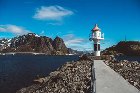 Lighthouse on the pier on the background of the mountains and the blue sky on the Lofoten Islands. Place for text or advertising.の写真素材