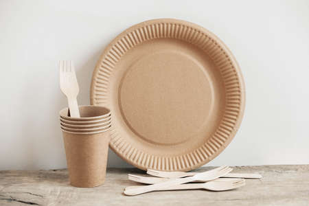 Wooden forks and paper cups with plates on kraft paper background. Eco friendly disposable tableware. Also used in fast food, restaurants, takeaways, picnics. Top view. Copy, empty space for text.の写真素材