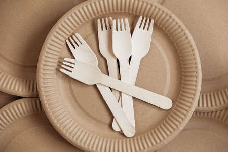 Wooden forks and paper cups with plates on kraft paper background. Eco friendly disposable tableware. Also used in fast food, restaurants, takeaways, picnics. Top view. Copy, empty space for text.の写真素材