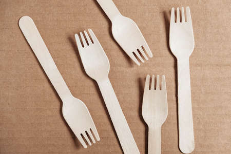 Wooden forks on a cardboard background. Eco friendly disposable tableware. Top view. Copy, empty space for text.の写真素材