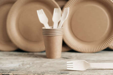 Wooden forks and paper cups with plates on kraft paper background. Eco friendly disposable tableware. Also used in fast food, restaurants, takeaways, picnics. Top view. Copy, empty space for text.の写真素材