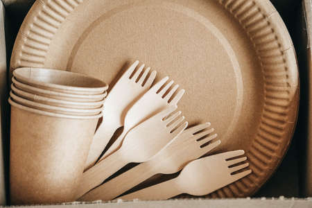 Wooden forks and paper cups with plates on kraft paper background. Eco friendly disposable tableware. Also used in fast food, restaurants, takeaways, picnics. Top view. Copy, empty space for text.の写真素材