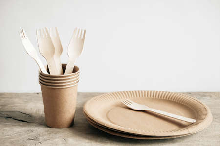 Wooden forks and paper cups with plates on kraft paper background. Eco friendly disposable tableware. Also used in fast food, restaurants, takeaways, picnics. Top view. Copy, empty space for text.の写真素材