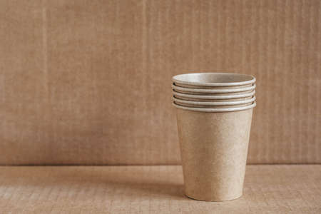 Wooden forks and paper cups with plates on kraft paper background. Eco friendly disposable tableware. Also used in fast food, restaurants, takeaways, picnics. Top view. Copy, empty space for text.の写真素材