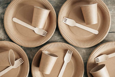 Wooden forks and paper cups with plates on kraft paper background. Eco friendly disposable tableware. Also used in fast food, restaurants, takeaways, picnics. Top view. Copy, empty space for text.の写真素材