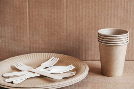 Wooden forks and paper cups with plates on kraft paper background. Eco friendly disposable tableware. Also used in fast food, restaurants, takeaways, picnics. Top view. Copy, empty space for text.の写真素材