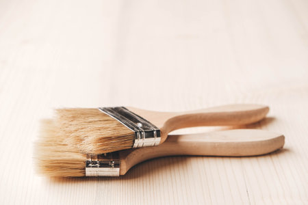 Varnishing natural wood with paint brush in brown color. Copy, empty space for text.