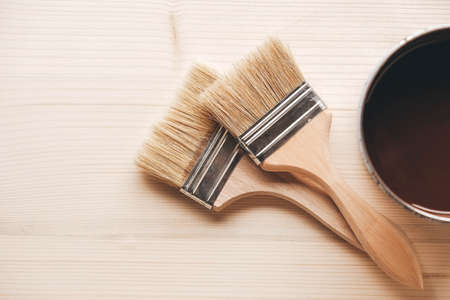 Paint brushes on a jar with brown paint on a wooden background. Repairing concept. Top view. Copy, empty space for text.の写真素材