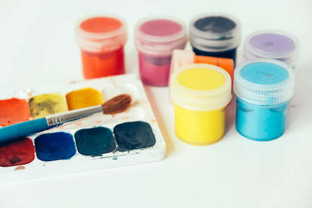 Colorful gouache paints and brush for painting on white wooden table. Top view. Copy, empty space for text.の写真素材