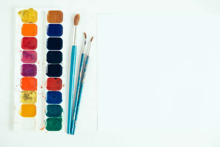 Colorful gouache paints and brush for painting on white wooden table. Top view. Copy, empty space for text.の写真素材