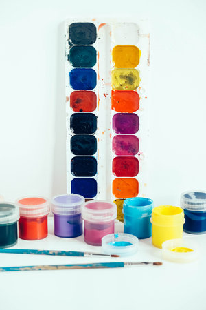 Colorful gouache paints and brush for painting on white wooden table. Top view. Copy, empty space for text.の写真素材