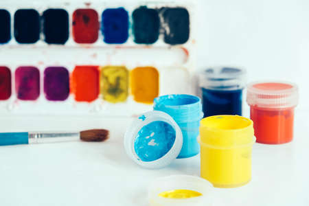 Colorful gouache paints and brush for painting on white wooden table. Top view. Copy, empty space for text.の写真素材