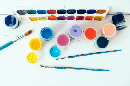 Colorful gouache paints and brush for painting on white wooden table. Top view. Copy, empty space for text.の写真素材