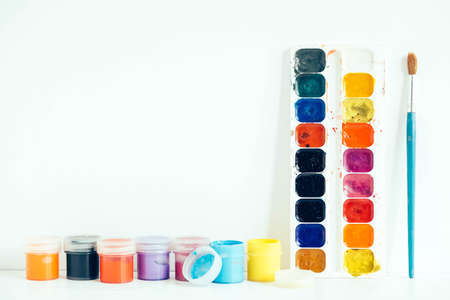 Colorful gouache paints and brush for painting on white wooden table. Top view. Copy, empty space for text.の写真素材
