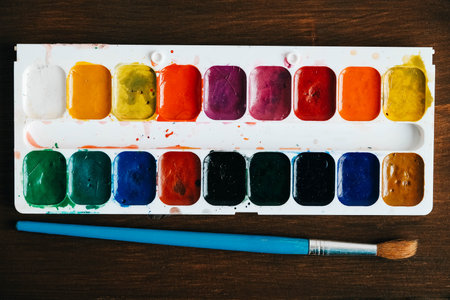 Set of watercolor paints with a brush for painting on a dark wooden background. Top view. Copy, empty space for text.の写真素材