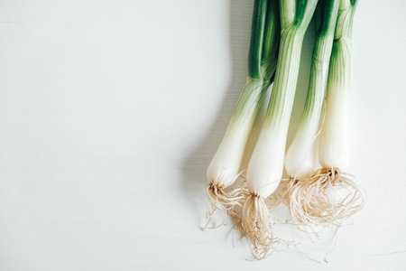 Bunch of fresh green onions on a white wooden background. Top view. Copy, empty space for text.