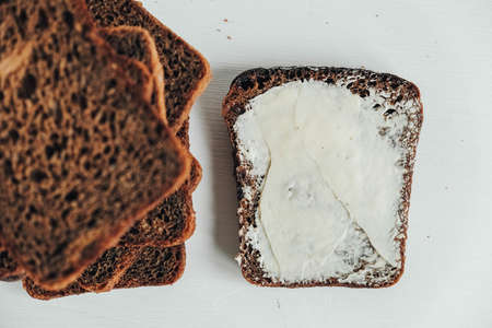 Sliced of brown bread with butter on a white wooden background. Top view. Copy, empty space for text.の写真素材
