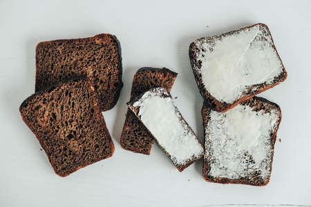 Sliced of brown bread with butter on a white wooden background. Top view. Copy, empty space for text.の写真素材