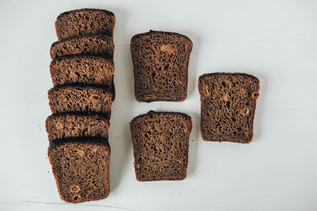 Sliced of brown bread with butter on a white wooden background. Top view. Copy, empty space for...