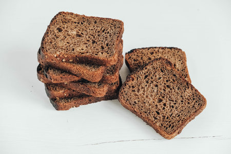 Sliced of brown bread with butter on a white wooden background. Top view. Copy, empty space for...
