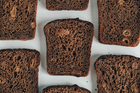 Sliced of brown bread with butter on a white wooden background. Top view. Copy, empty space for...