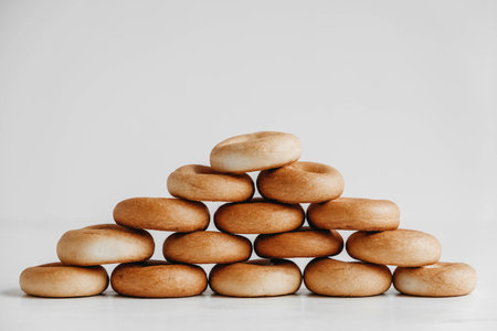 Drying or mini round bagels in the shape of a pyramid on a white wooden background. Copy, empty space for text.の写真素材
