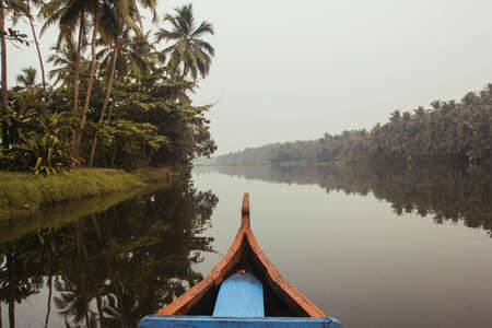 Wooden boat on the backwater canals on a background of tropical forest with palm trees. Copy, empty space for text.の写真素材
