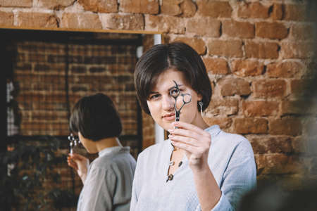 Young beautiful hairdresser woman with scissors in hand in the barbashop salon. Barbershop advertising concept. Place for text or advertising.の写真素材