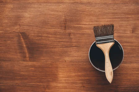 Paint brush on a jar with brown paint on a wooden background. Repairing concept. Top view. Copy, empty space for text.の写真素材