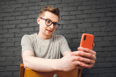 Young man in shirt and glasses he looks at the laptop in amazement and with a funny face sitting at...