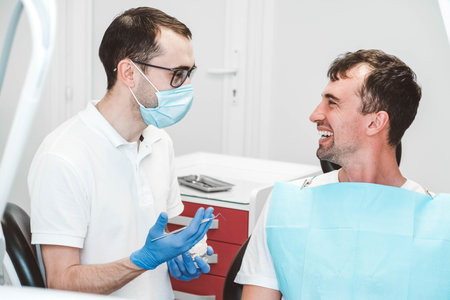 Dentist examines the teeth of a male patient on a dentist's chair. Copy, empty space for text.の写真素材