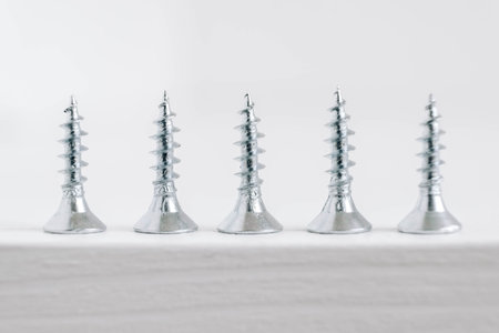 Metal tapping screws for wood on white wooden background. Construction equipment concept. Top view. Copy, empty space for text.の写真素材