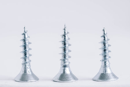 Metal tapping screws for wood on white wooden background. Construction equipment concept. Top view. Copy, empty space for text.の写真素材