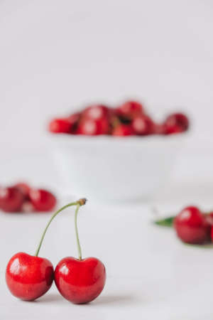 Fresh juicy red cherries in a white plate on the white wooden background. Copy, empty space for text.の写真素材