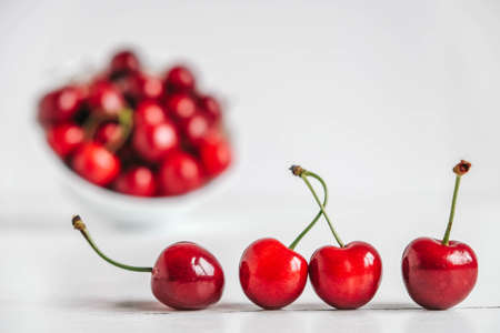 Fresh juicy red cherries in a white plate on the white wooden background. Copy, empty space for text.の写真素材
