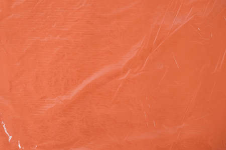 Wrinkled transparent plastic texture on an orange background. Transparent cellophane texture on an orange backing. Top view. Copy, empty space for text.の写真素材