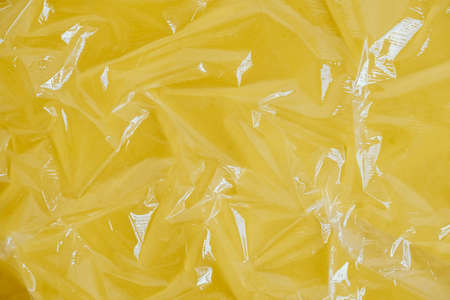 Wrinkled transparent plastic texture on an yellow background. Transparent cellophane texture on an yellow backing. Top view. Copy, empty space for text.の写真素材